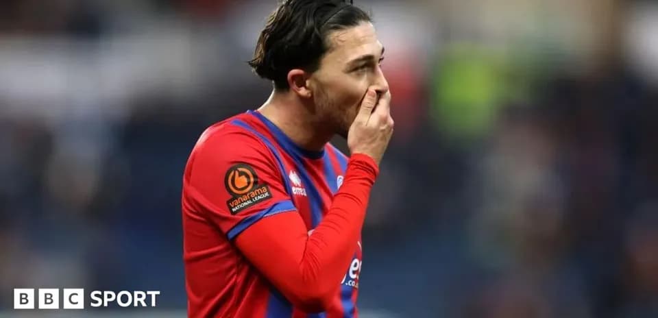 Jugador de fútbol con camiseta roja y azul, pensativo