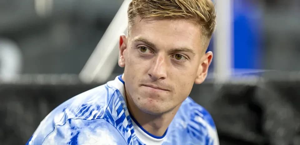 Jugador sentado con camiseta azul en el banquillo