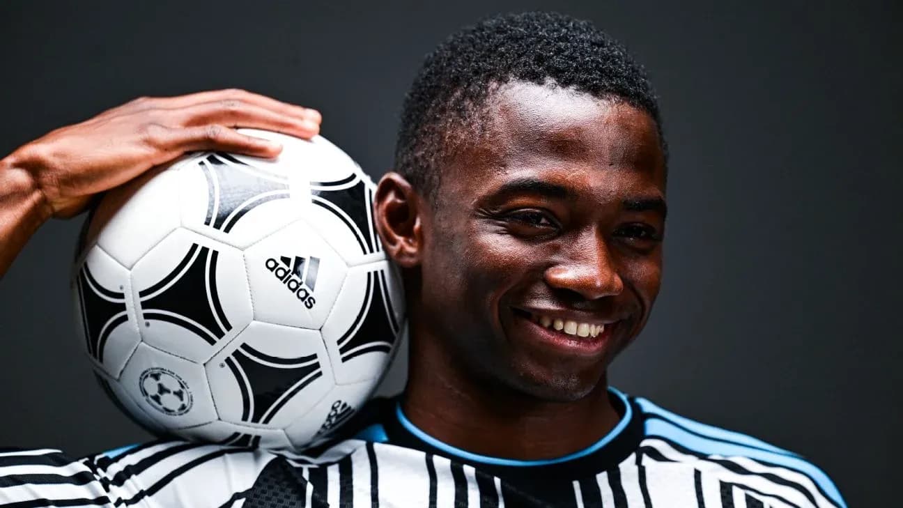 Jugador sosteniendo un balón de fútbol con una mano