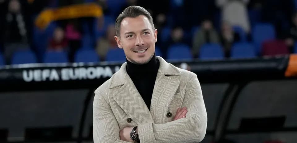 Hombre sonriente con abrigo en estadio de fútbol