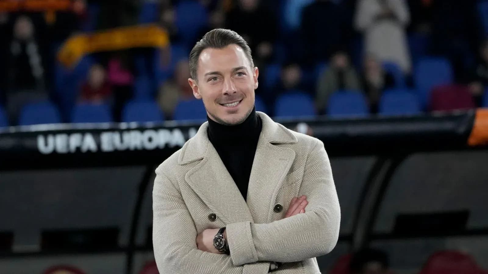 Hombre sonriente con abrigo en estadio de fútbol