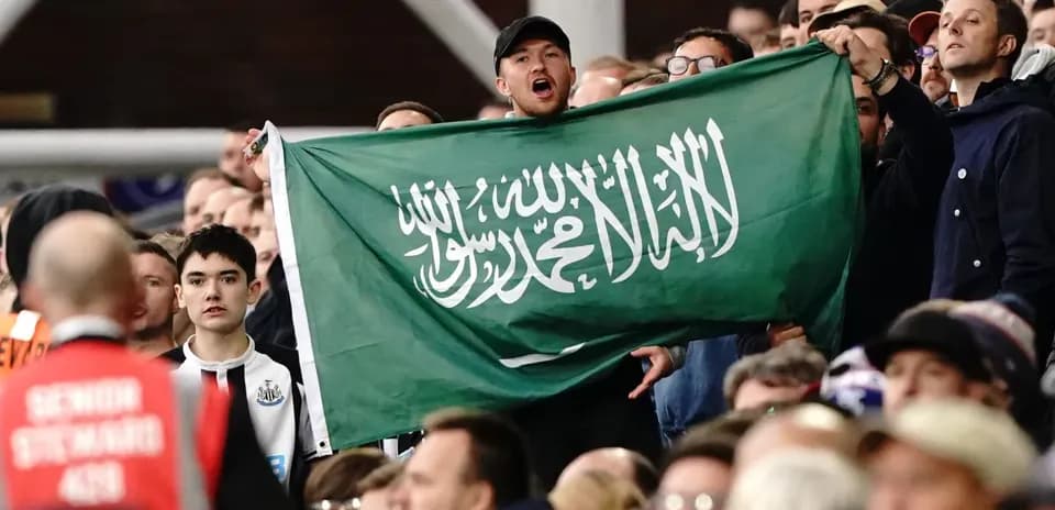 Afan en las gradas sosteniendo una bandera de Arabia Saudita