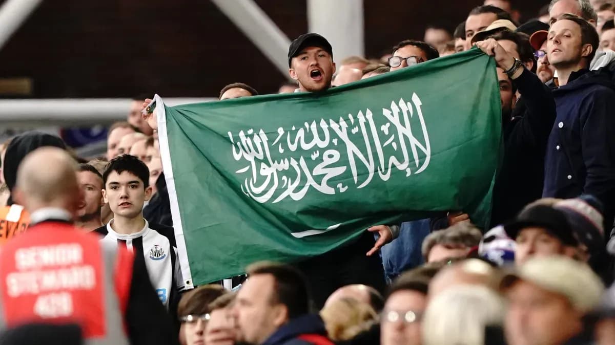 Afan en las gradas sosteniendo una bandera de Arabia Saudita
