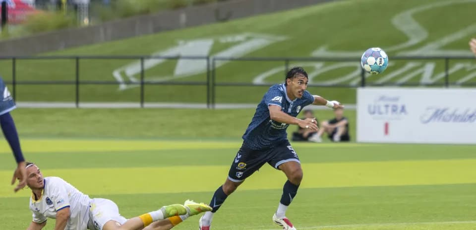 Jugador en el suelo mientras otro persigue el balón