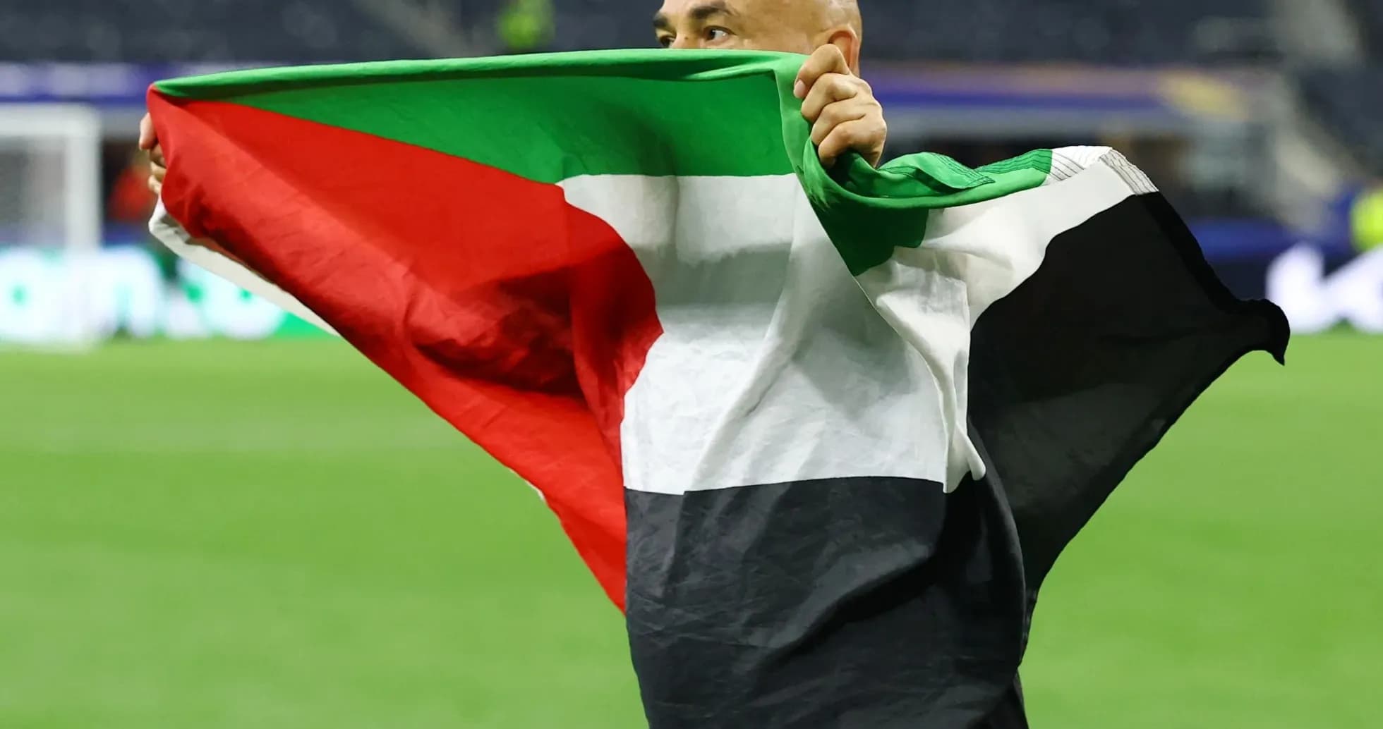 Persona sosteniendo una bandera de Palestina en el campo
