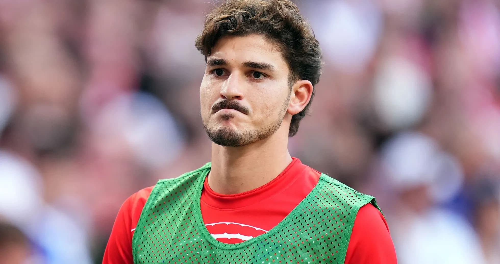 Jugador en la banca con chaleco de entrenamiento verde