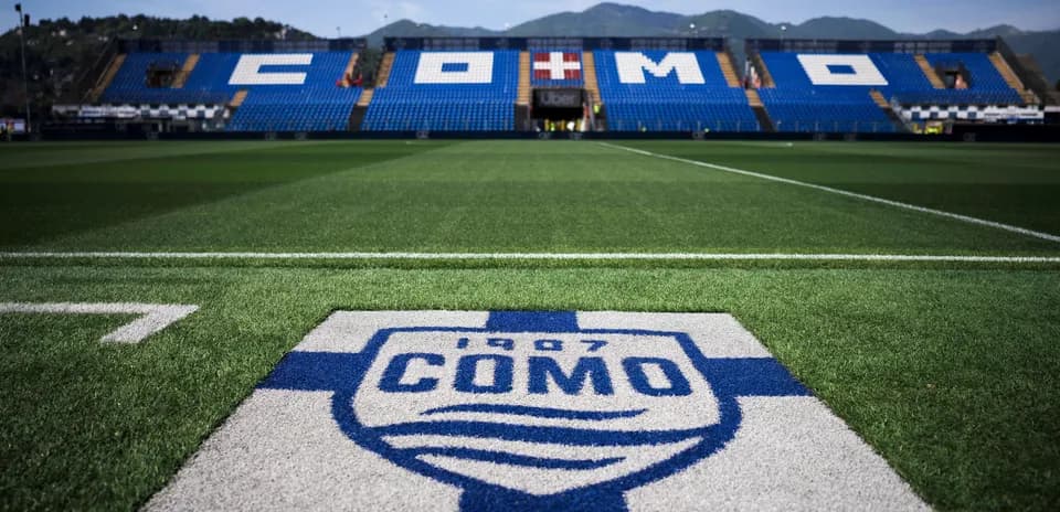 Campo de fútbol con logo de Como 1907 en primer plano