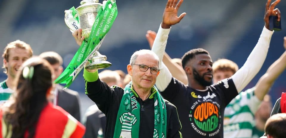 Hombre levantando trofeo con bufanda verde en celebración