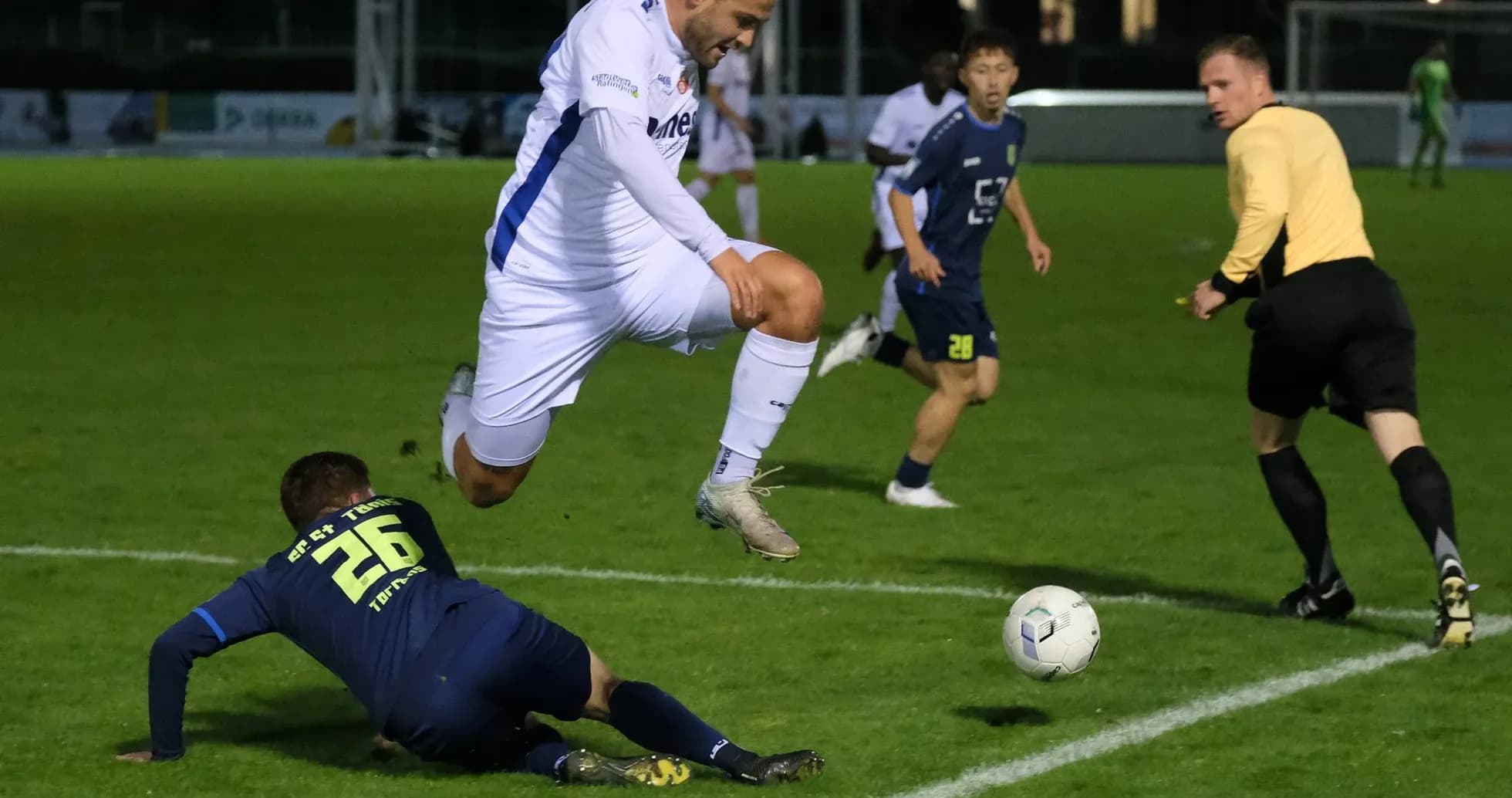 Jugador saltando sobre oponente en partido de fútbol