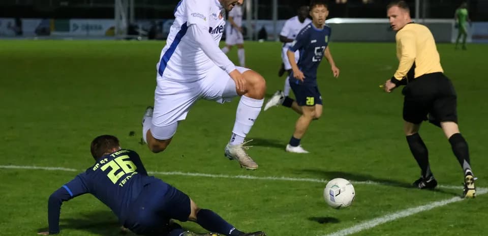 Jugador saltando sobre oponente en partido de fútbol