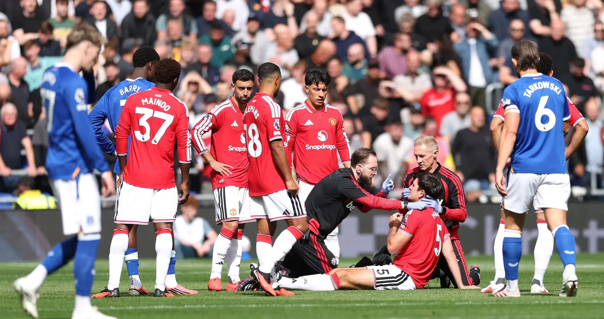 Jugadores de Manchester United atienden a compañero lesionado