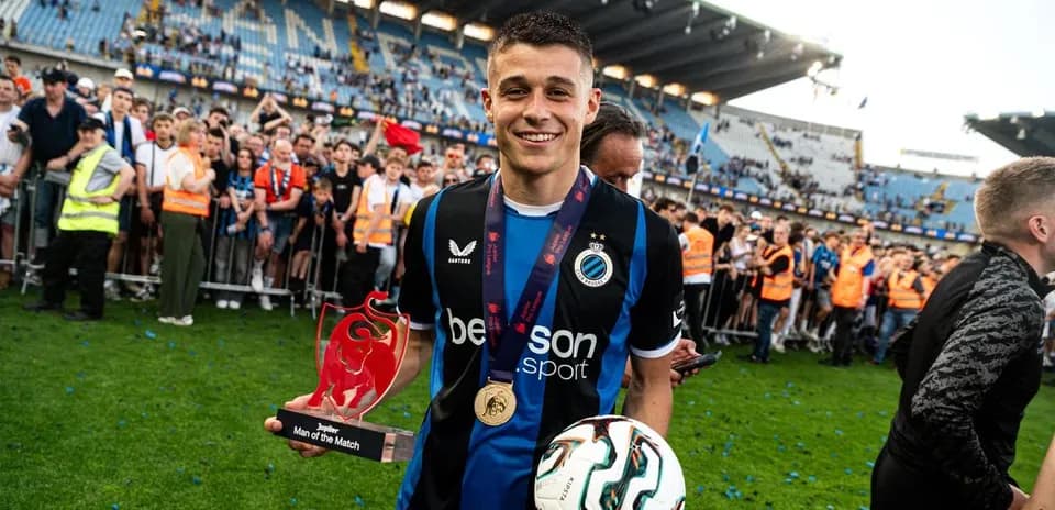 Jugador sosteniendo trofeo y balón en celebración