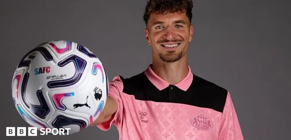 Jugador sosteniendo un balón de fútbol sonriente