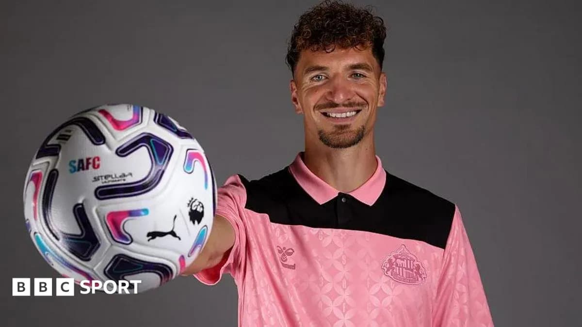 Jugador sosteniendo un balón de fútbol sonriente