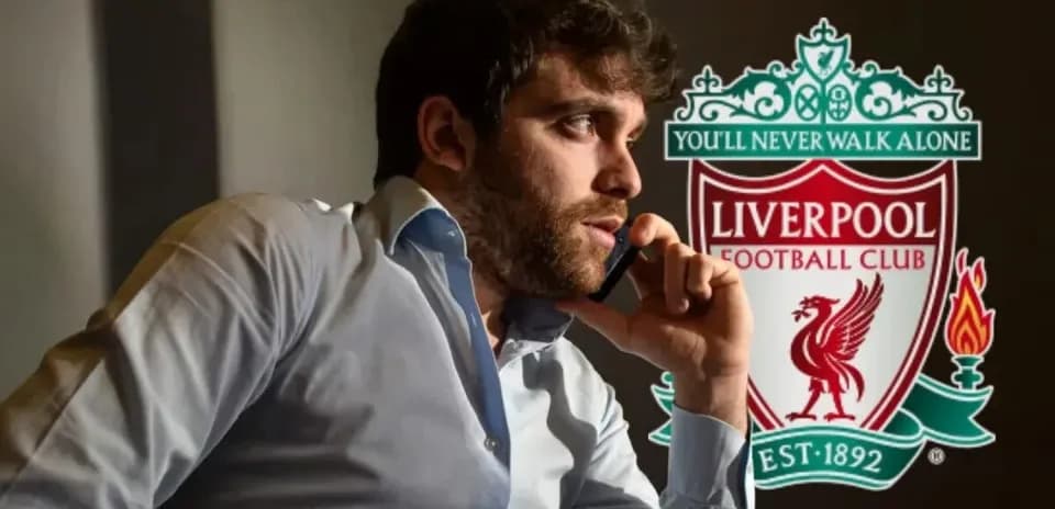 Hombre hablando por teléfono junto al escudo de Liverpool
