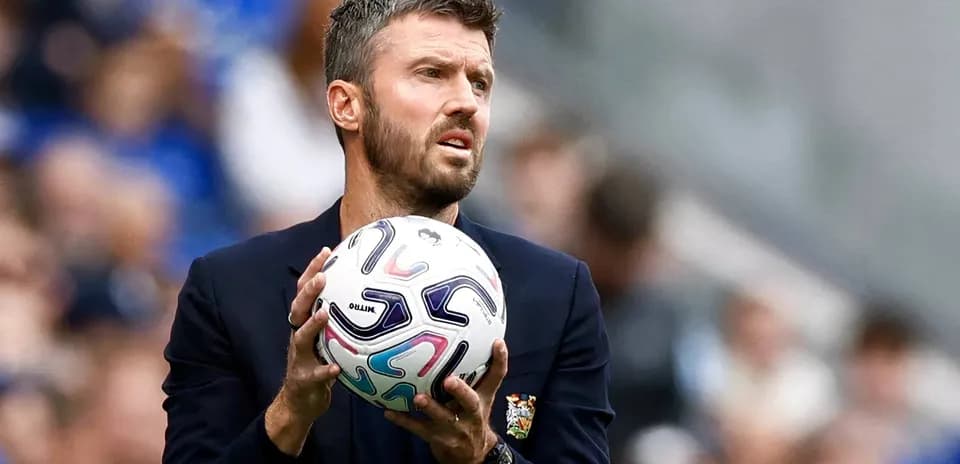 Entrenador sosteniendo un balón en la banda