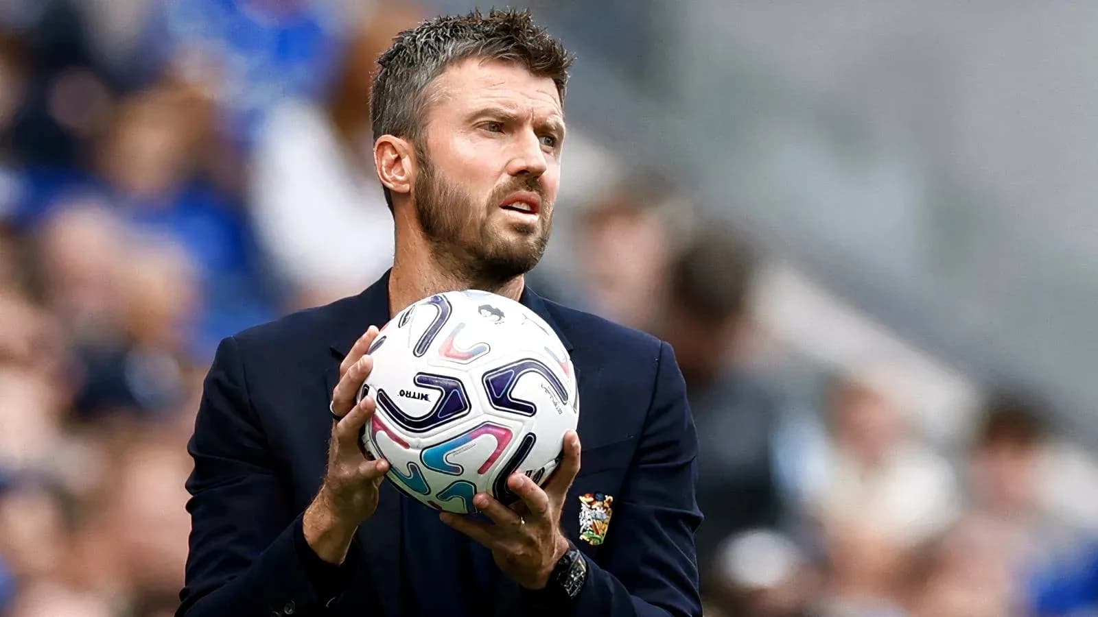 Entrenador sosteniendo un balón en la banda