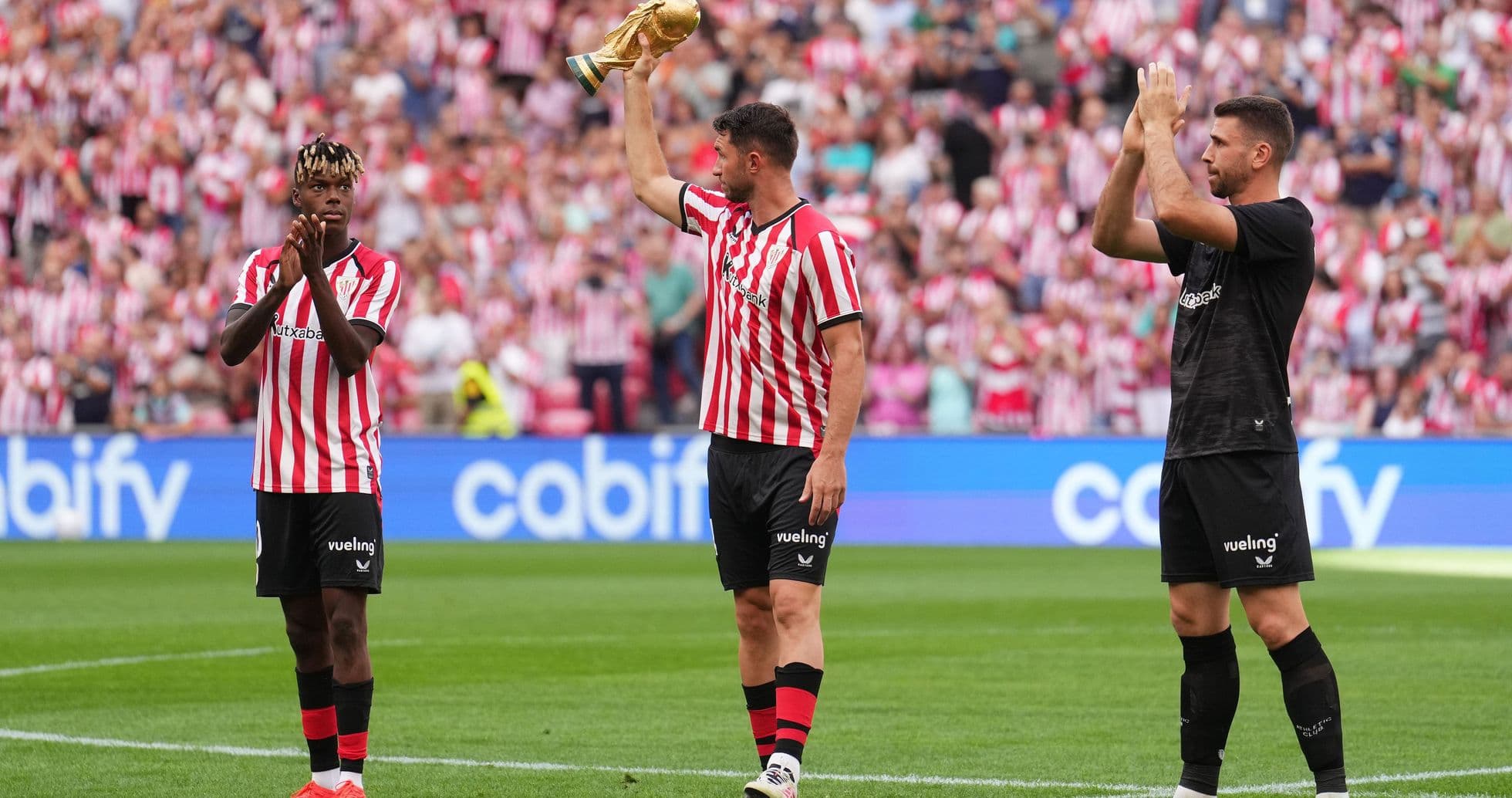 Jugadores de Athletic Club celebrando con trofeo en el campo