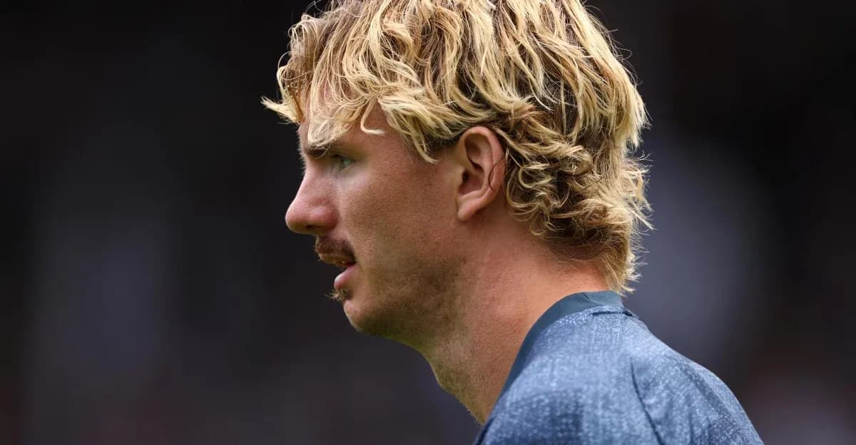 Jugador con cabello rizado y bigote en perfil