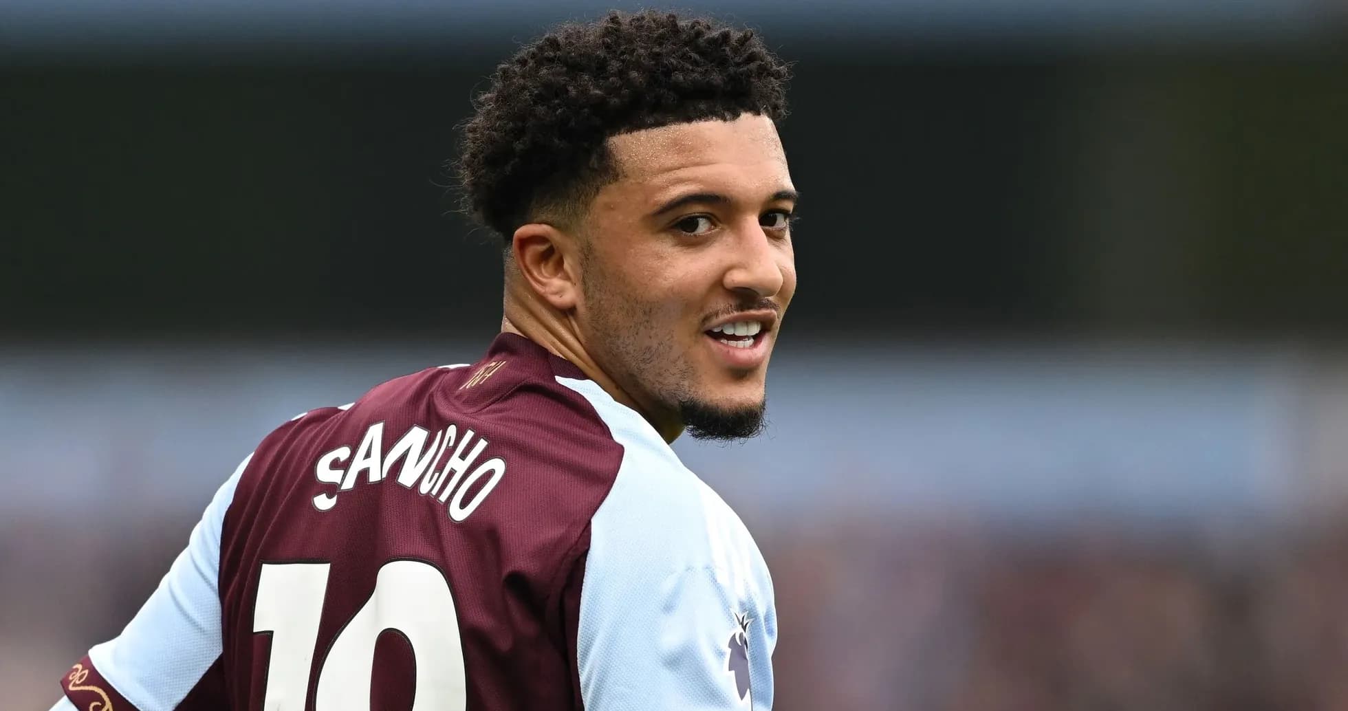 Jugador con camiseta de Aston Villa sonriendo hacia atrás