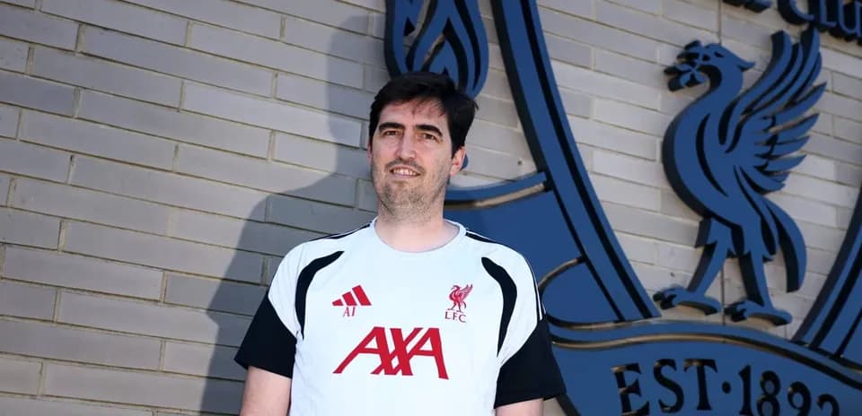 Persona posando frente al escudo de Liverpool FC