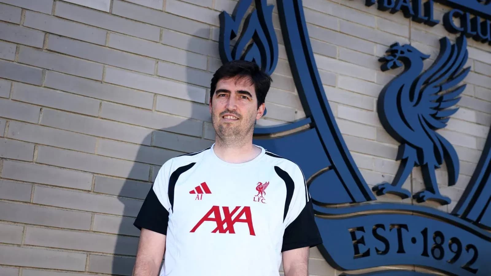 Persona posando frente al escudo de Liverpool FC