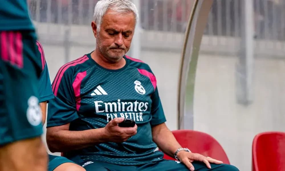 Entrenador de Real Madrid revisando su teléfono en banco