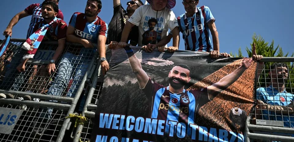 Aficionados sosteniendo un banner de bienvenida en Trabzon