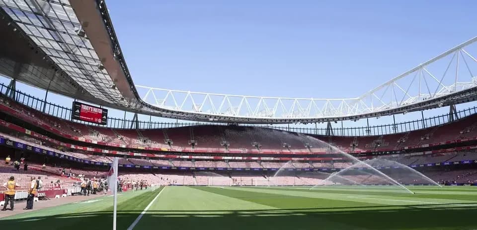Estadio con césped regado y asientos vacíos