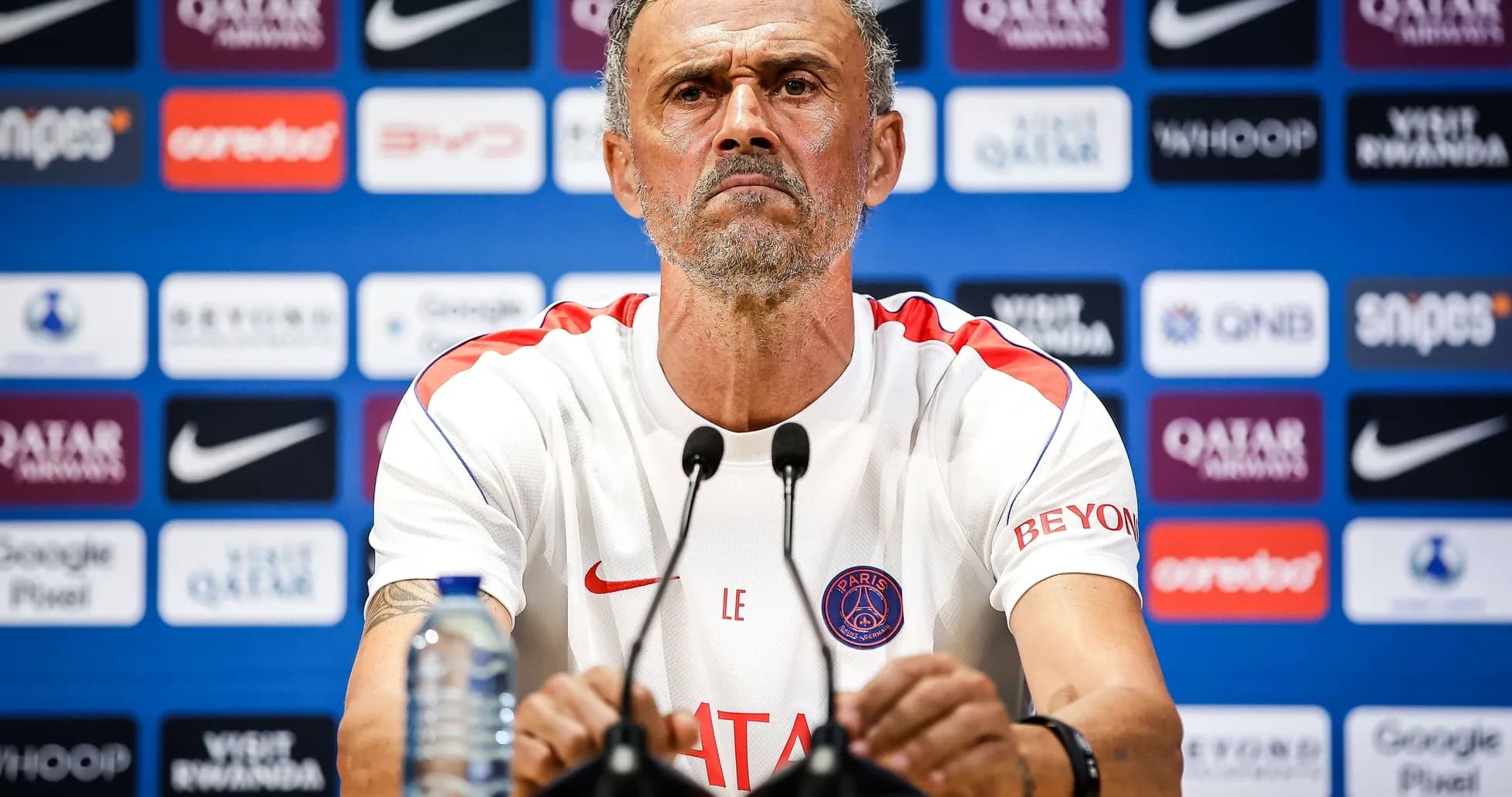 Entrenador en conferencia de prensa con logotipos de patrocinadores