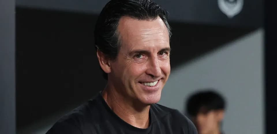 Entrenador sonriendo en banquillo durante partido