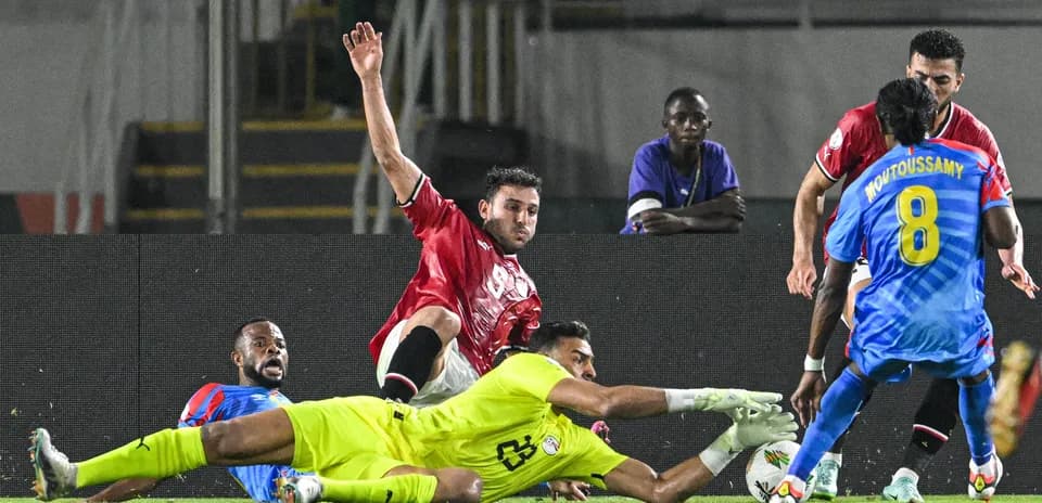 Jugador cae mientras el portero atrapa el balón