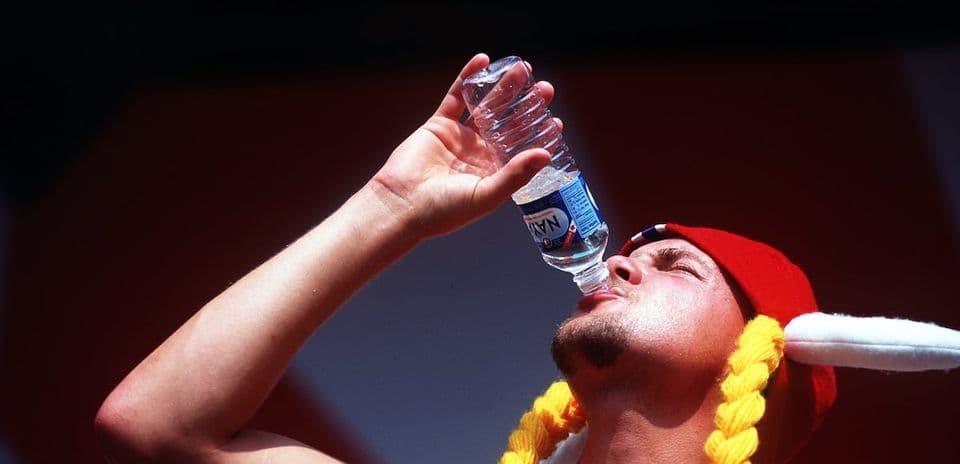 Hombre bebiendo agua de botella en evento deportivo