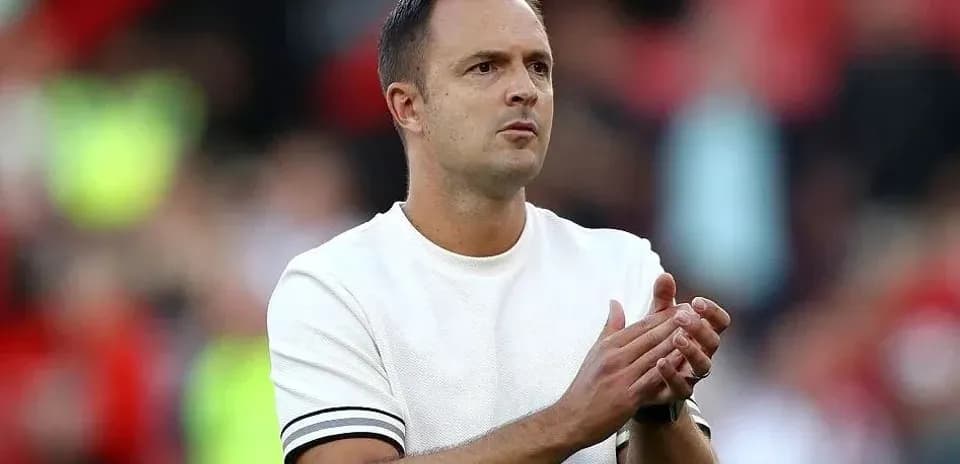 Entrenador aplaudiendo en el banquillo durante el partido