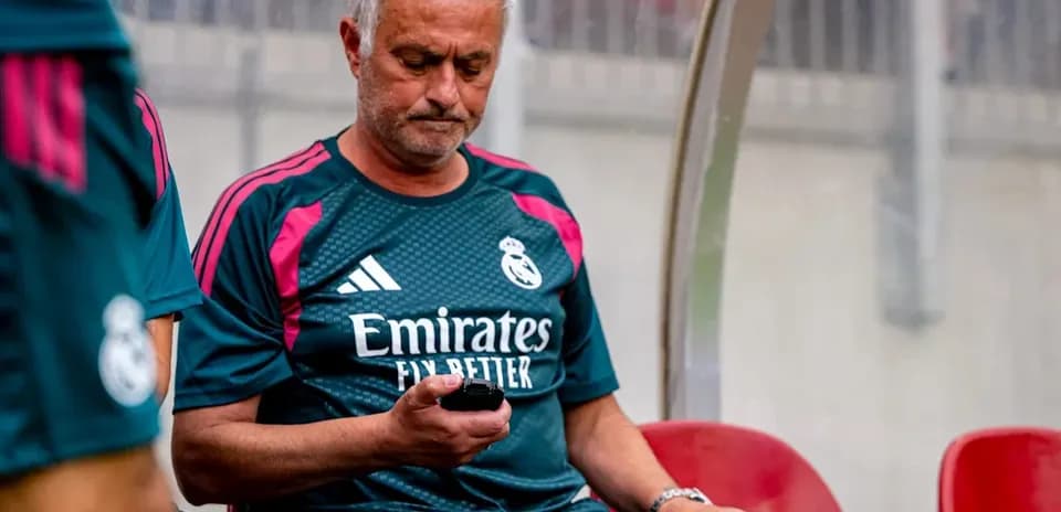 Entrenador sentado en el banquillo usando teléfono