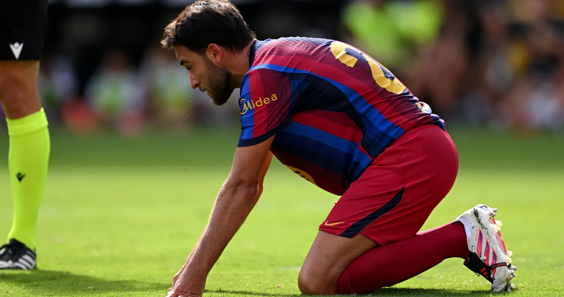 Jugador de Barcelona arrodillado en el campo de juego
