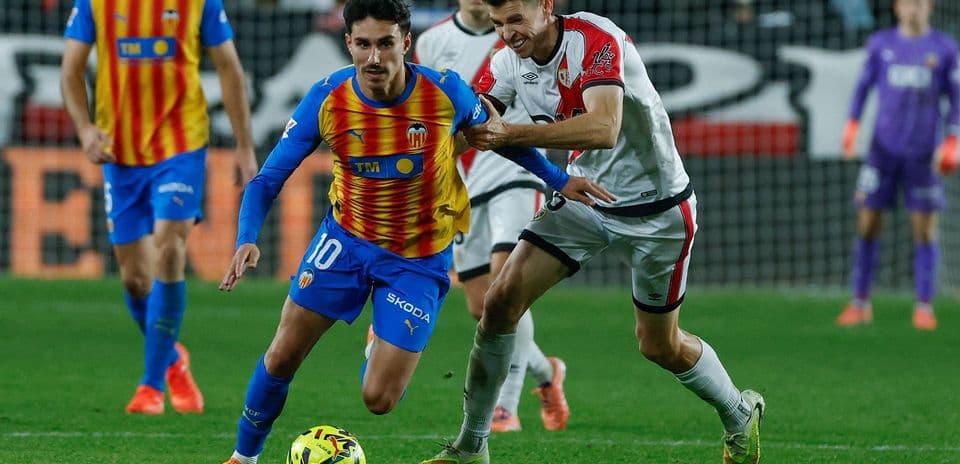 Jugador de Valencia driblando a un rival de Rayo Vallecano