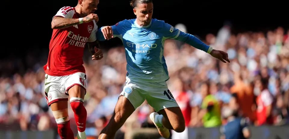 Jugadores de Arsenal y Manchester City luchando por el balón