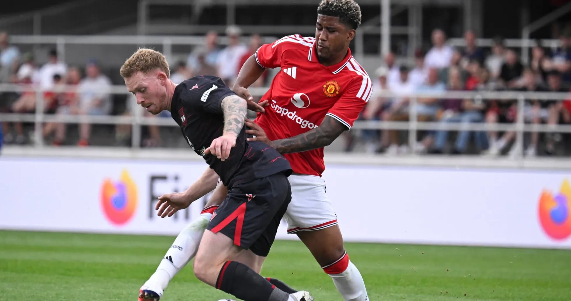 Jugador de Manchester United defendiendo a rival en el campo