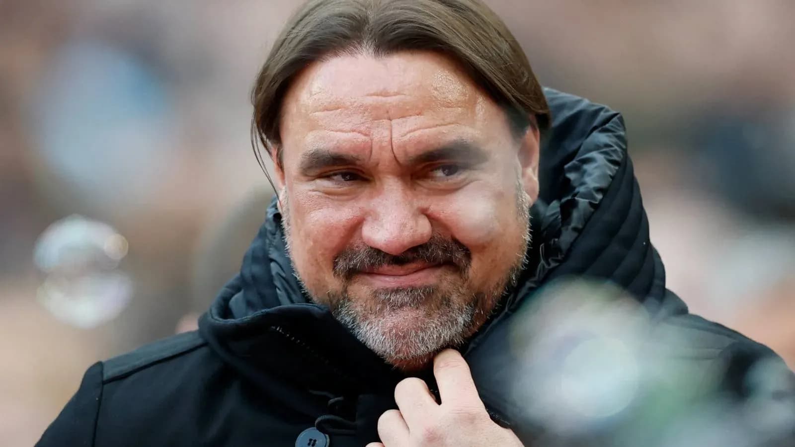 Entrenador con chaqueta negra en el banquillo