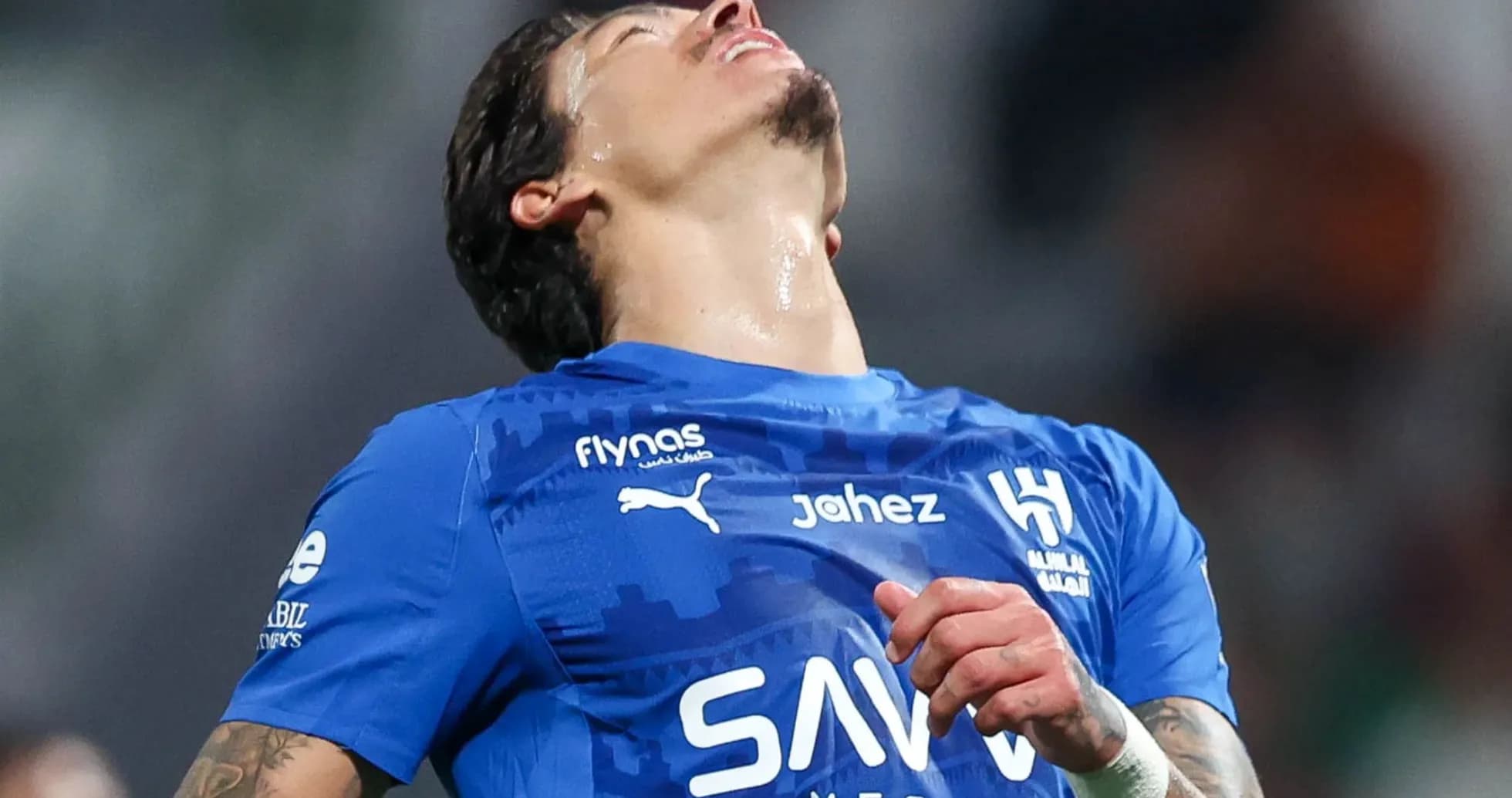 Jugador con camiseta azul mirando hacia arriba en el campo