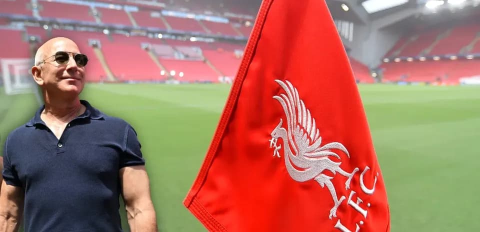 Hombre posando junto a bandera de Liverpool en estadio
