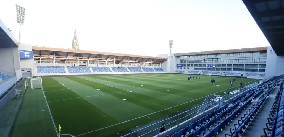 Campo de fútbol con jugadores entrenando en el fondo