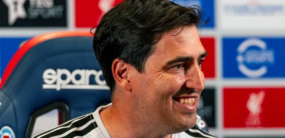 Entrenador sonriendo en la sala de prensa