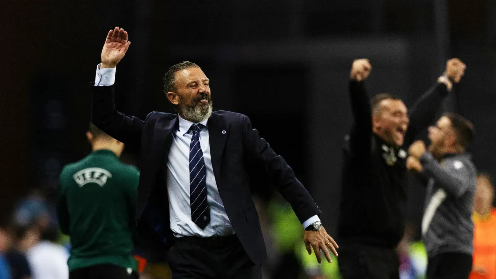 Entrenador celebrando victoria con brazos levantados