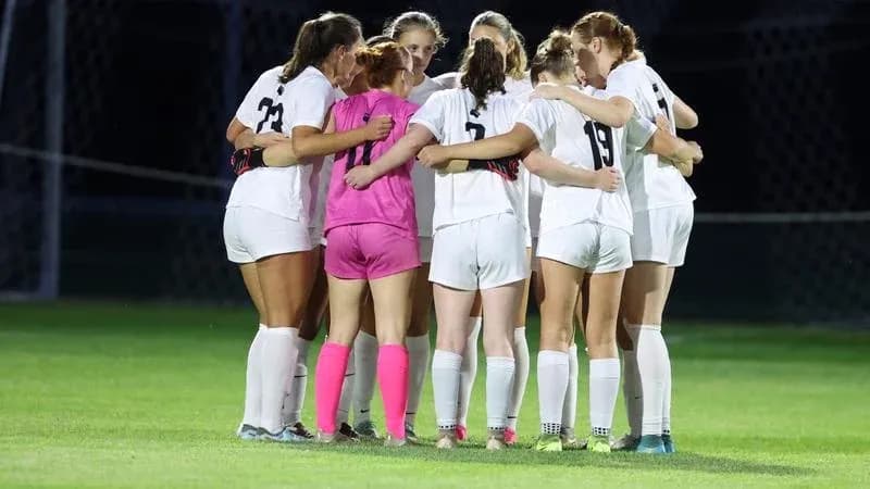 Jugadoras de fútbol formando un círculo en equipo