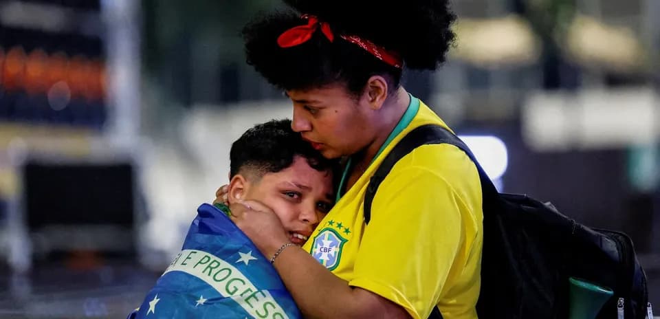 Mujer abrazando a niño envuelto en bandera de Brasil
