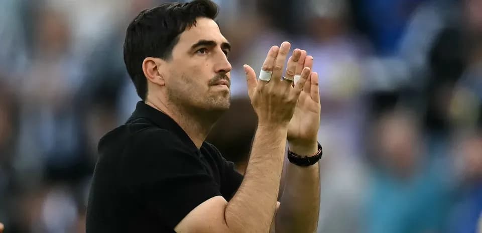 Entrenador aplaudiendo en el campo durante el partido