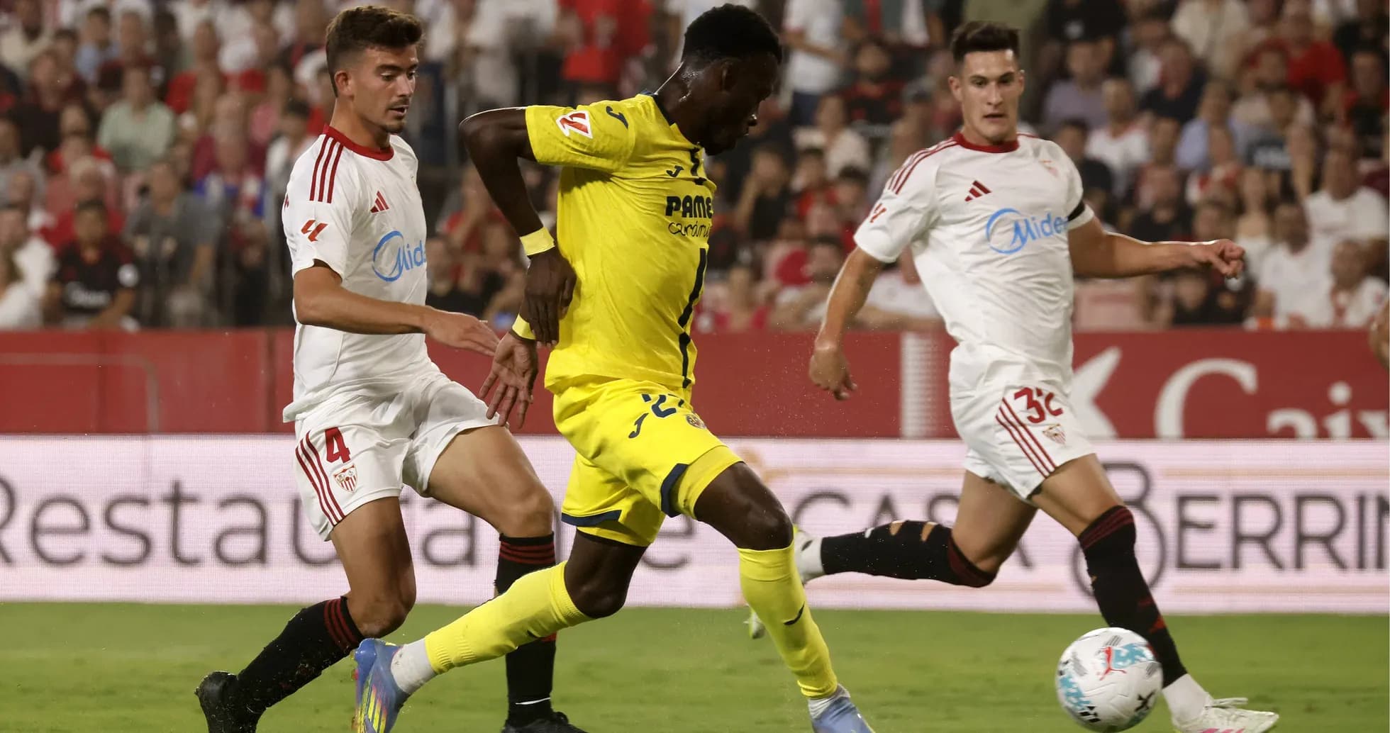 Jugador del Villarreal driblando entre defensores del Sevilla