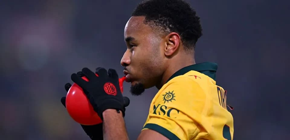Jugador sosteniendo un balón rojo antes del partido